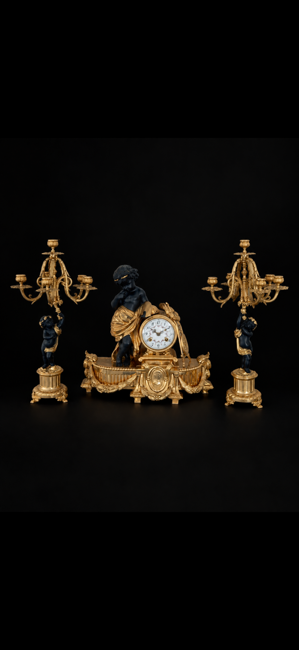 Garniture de cheminée d'après Auguste Moreau, pendule et paire de candélabres aux putti, bronze doré et patiné